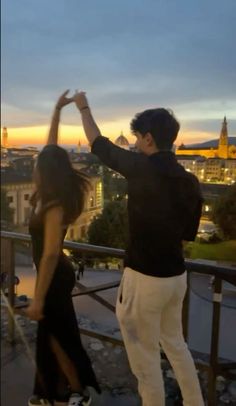 a man and woman dancing on top of a building