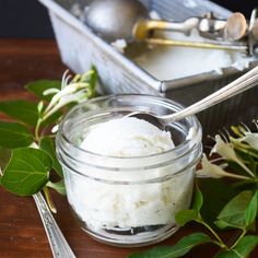 there is a spoon and some sugar in a jar on the table next to flowers