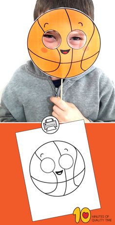 a young boy holding up a paper mask with an image of a basketball ball on it