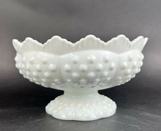 a white glass bowl sitting on top of a black countertop next to a gray wall