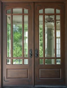 two brown double doors with glass panels on brick wall and sidelights above the door