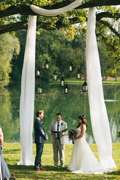 a bride and groom are standing under an arbor with lanterns hanging from the branches over them