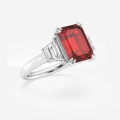 Get lost in the mesmerizing facets of this emerald cut three stone ring, featuring a striking red ruby that's sure to turn heads. The emerald cut's clean lines and geometric precision bring an enchanting shimmer to the vibrant gem, while its elongated shape creates an elegant look on the finger. Accented by diamond side stones, this emerald cut ruby ring embodies old world sophistication. Formal Red Ruby Ring With Three Stones, Formal Ruby Three Stone Ring, Formal Red Three Stone Ruby Ring, Gia Certified Baguette Cut Ruby Ring, Luxury Red Three Stone Jewelry, Red Baguette Cut Diamond Ring, Luxury Red Three-stone Jewelry, Three Stone Classic Jewelry With Lab-created Ruby, Classic Three Stone Lab-created Ruby Jewelry