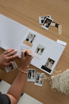 a person writing on a piece of paper next to pictures and flowers with photos pinned to them