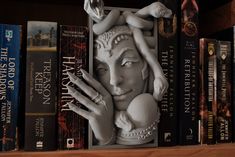 a book shelf with several books on it and a statue of a woman's head