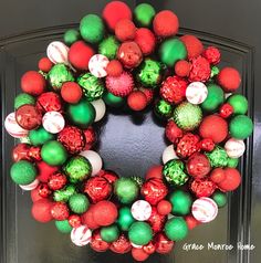 a christmas wreath on the front door with ornaments hanging from it's sides and an ornament in the middle