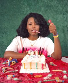 a woman sitting at a table with a birthday cake and toothbrush in her mouth