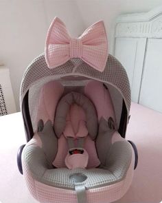 a baby's car seat with a pink bow on the top and grey bottom