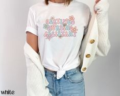 Get ready to be OBSESSED with this cute spring floral retro CNA shirt! Buy today for yourself or for someone special!  Q U I C K F A C T S  ✦ Unisex Bella+Canvas 3001 available in: white, ash, natural, heather peach, soft pink, yellow, mint, and light blue ✦ Light fabric ✦ Retail fit/ runs true to size ✦ Printed and shipped from the USA with love  S I Z I N G  ✦ Runs true to size ✦ Solid colors are 100% cotton except Ash - 99% cotton and 1% polyester ✦ Heather colors are 52% cotton, 48% polyeste Spring Vintage Shirt With Letter Print, Vintage Letter Print Shirt For Spring, Vintage Spring Shirt With Letter Print, Cute Relaxed Fit Shirt For Spring, Infusion Nurse, Funny Nurse Shirts, Certified Nursing Assistant, Iv Therapy, Funny Nurse