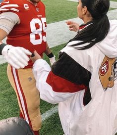 a man and woman dressed up in football uniforms on the sidelines at a game