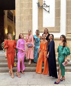 a group of women standing next to each other in front of a building with stairs