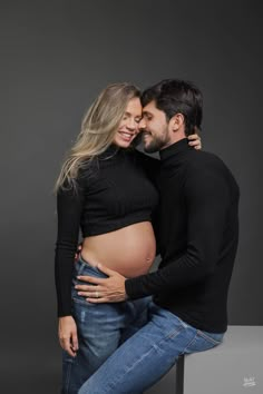 a pregnant man and woman pose for the camera with their belly wrapped around each other