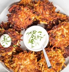 some fried food on a white plate with a small bowl of ranch dressing next to it