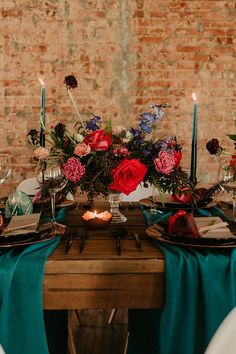 the table is set with candles and flowers on it, along with plates and napkins