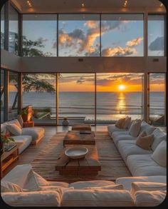 a living room with large windows overlooking the ocean and sunset in the distance at dusk