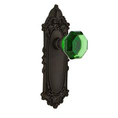 an ornate door handle with a green glass knob on it's back plate,