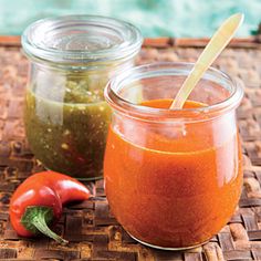 two jars filled with different colored sauces on top of a bamboo mat next to a pool