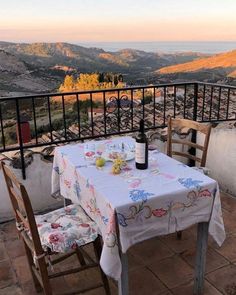 a table with two chairs and a bottle of wine sitting on top of it next to a balcony