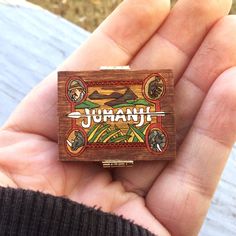 a hand holding a small wooden box with an image of the word juan on it