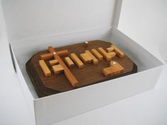 a wooden puzzle in a white box with the word game spelled out on it's side