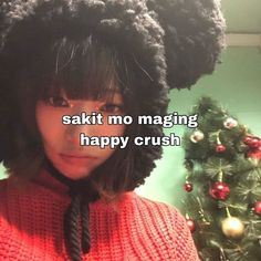 a woman with black hair wearing a red sweater next to a christmas tree that says sakit mo maging happy crush