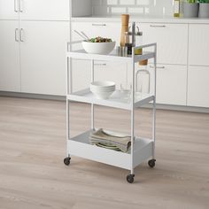 a kitchen cart with plates and bowls on it in the middle of a wooden floor