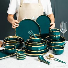 a person holding a green and gold dinnerware set