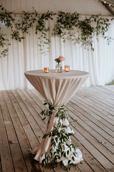 the table is set up with candles and greenery for an outdoor wedding reception at night