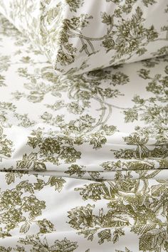 a close up view of a bed sheet with green flowers and leaves on white background