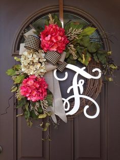 a wreath with the letter f on it and purple flowers is hanging from a front door