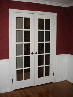 two white french doors in a room with red walls