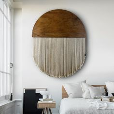 a bedroom with white walls and a round wooden wall hanging