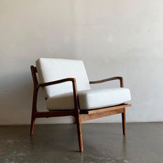 a white chair sitting on top of a cement floor next to a wooden frame wall