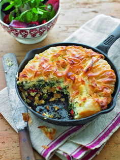 there is a pie in the pan on the table next to a bowl of salad