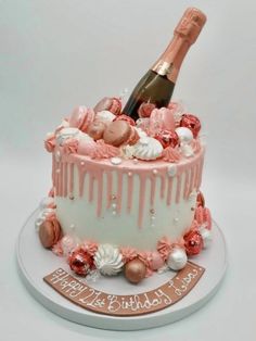 a birthday cake decorated with pink and white icing, champagne bottle in the middle