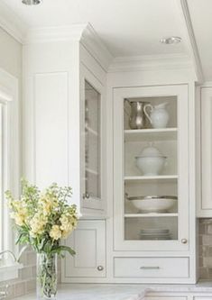 a kitchen with white cabinets and marble counter tops in the center is filled with flowers