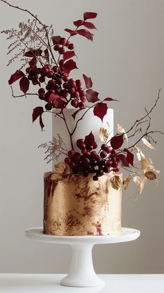 a white and gold cake with red berries on top