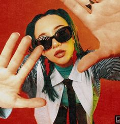 a woman with green hair wearing sunglasses and holding up her hand