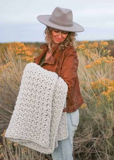 a woman wearing a hat and holding a crocheted blanket