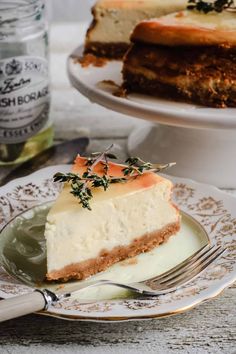 a slice of cheesecake on a plate with a fork and bottle of tea in the background