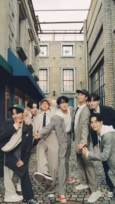 a group of young men standing next to each other on a brick road in front of tall buildings