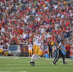 a football player throwing a ball on top of a field in front of a crowd