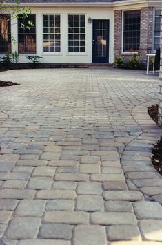 a brick driveway with a fire hydrant in the middle and a house behind it