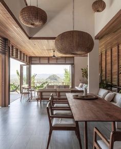 a large wooden table sitting under two hanging lights in a living room next to a window