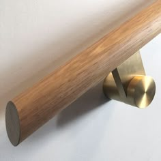 a wooden pole mounted to the side of a wall next to a metal hook on a white wall