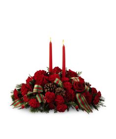 red flowers and pine cones are arranged in a centerpiece with three candles on each side