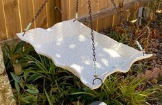 a bird bath hanging from a chain in the grass