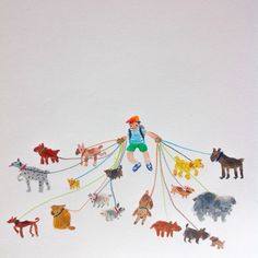 there is a boy that is playing with many toy animals on a string in the snow