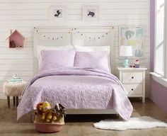 a bedroom with white walls and purple bedspread on the bed, along with teddy bears