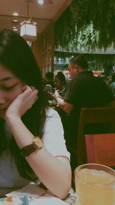 a woman sitting at a table with a plate of food in front of her face